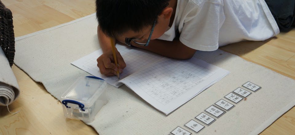 Child lying on floor writing in a notebook