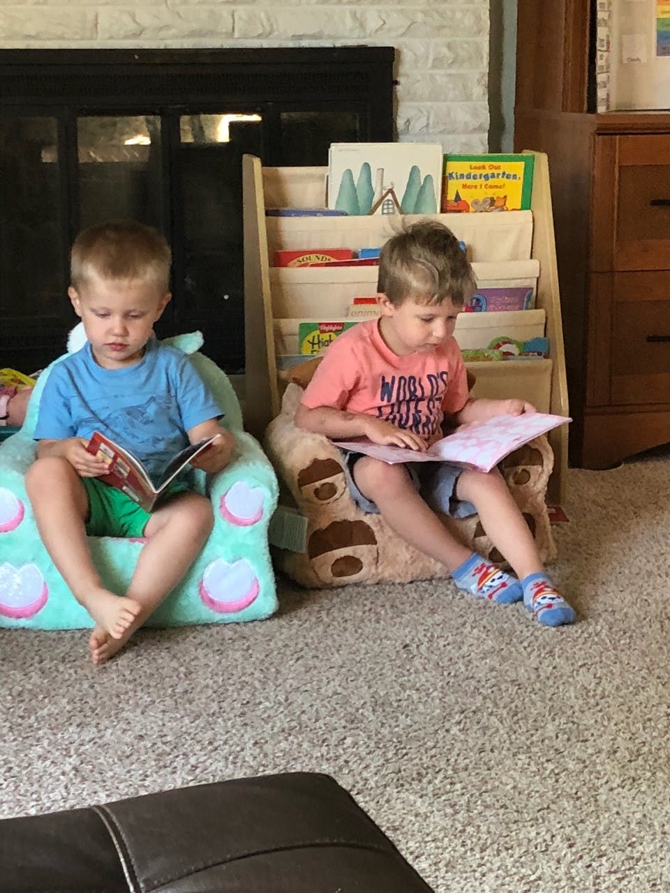 Two children sitting in chairs reading books