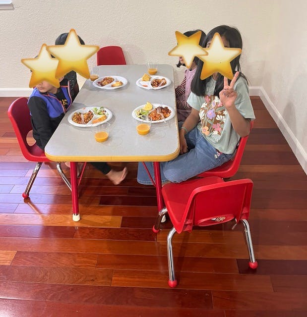 Children sitting at a table with plates of food and drinks