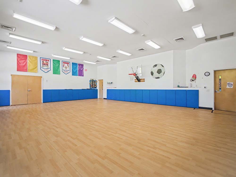 Empty gym room with light wood floors and blue wall padding