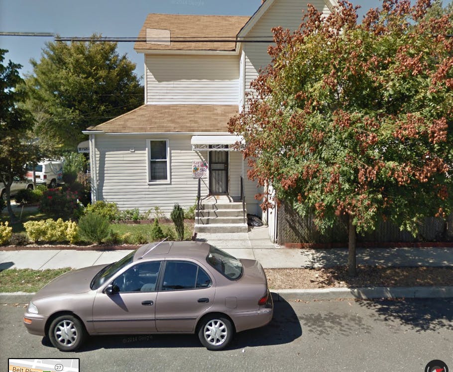 Car parked in front of a house with a tree