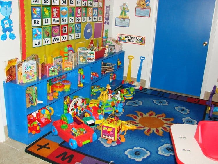 Playroom with blue shelves full of toys and a blue rug with a sun design