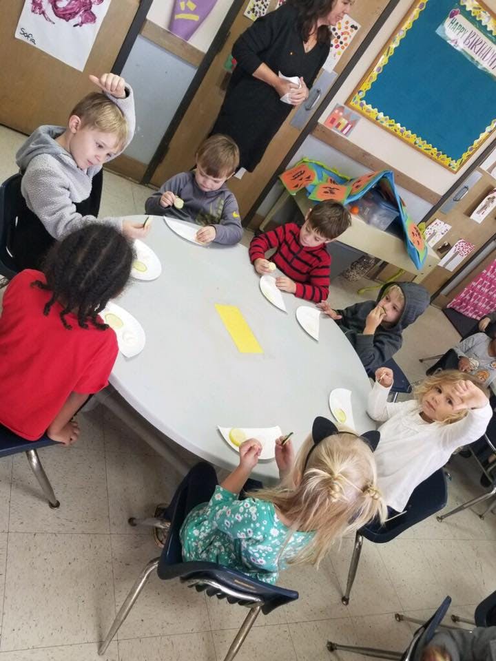 Children sitting around a table doing an activity with paper plates