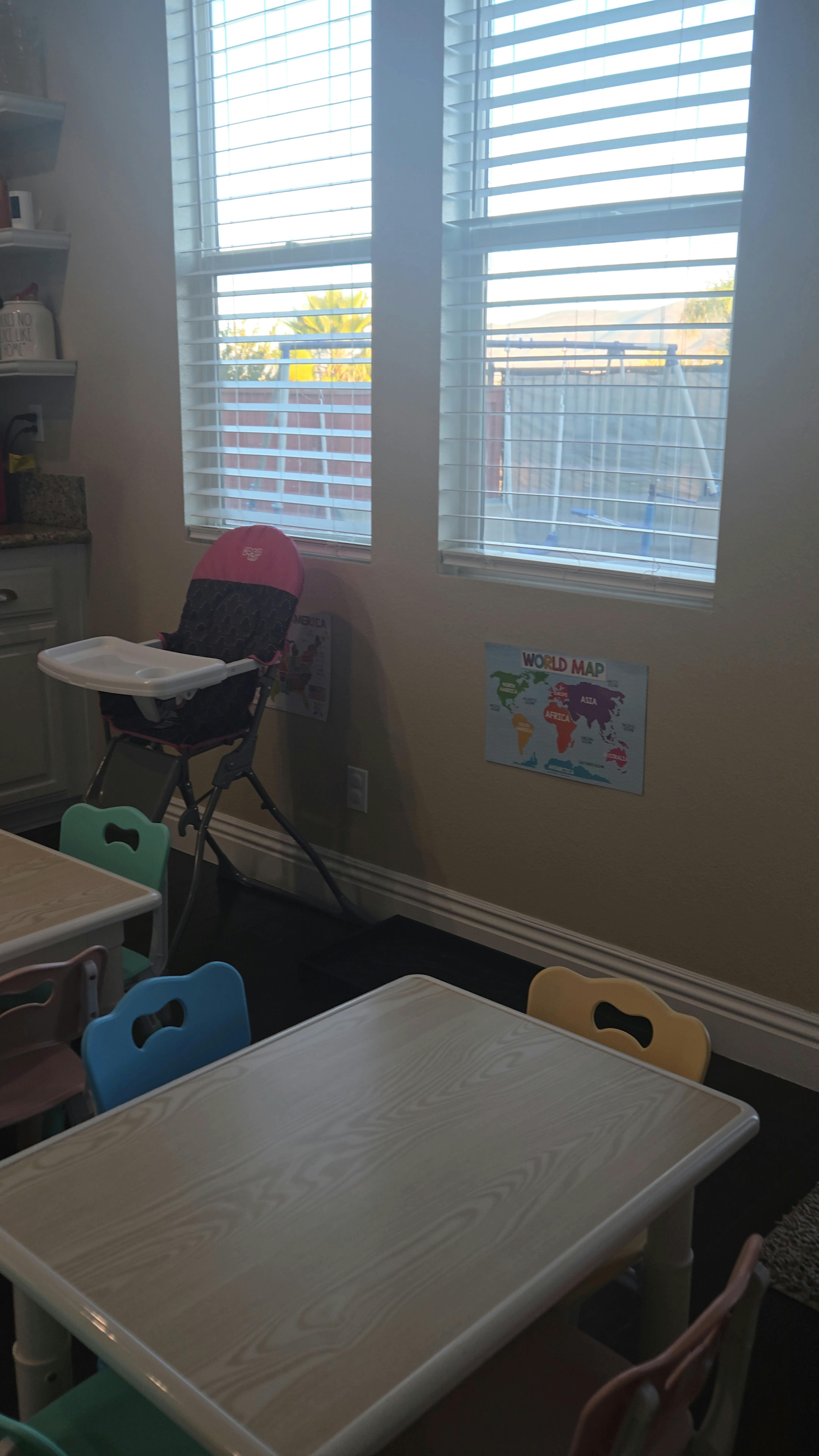 High chair and small tables with chairs in a room with windows
