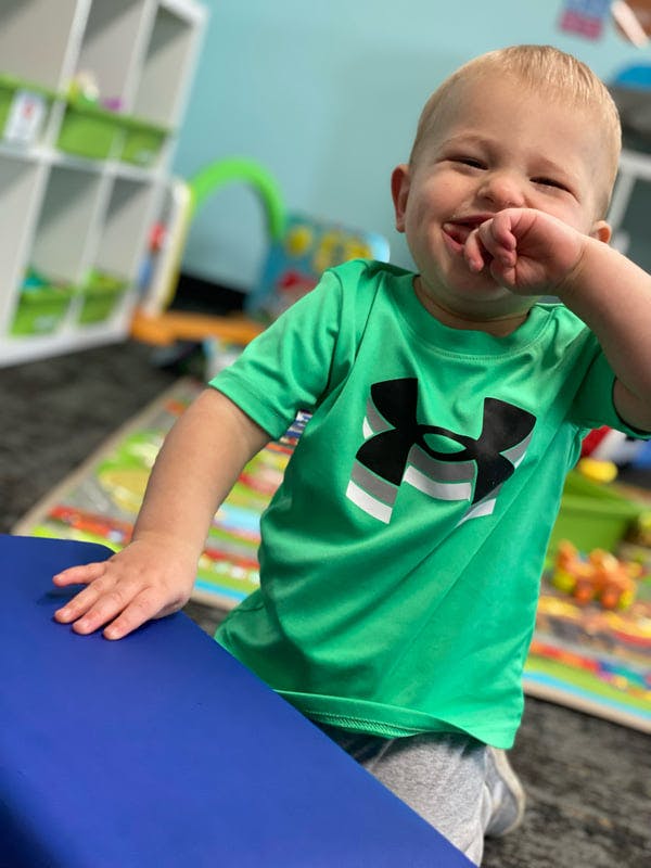 Child in a green shirt with hand on a blue surface