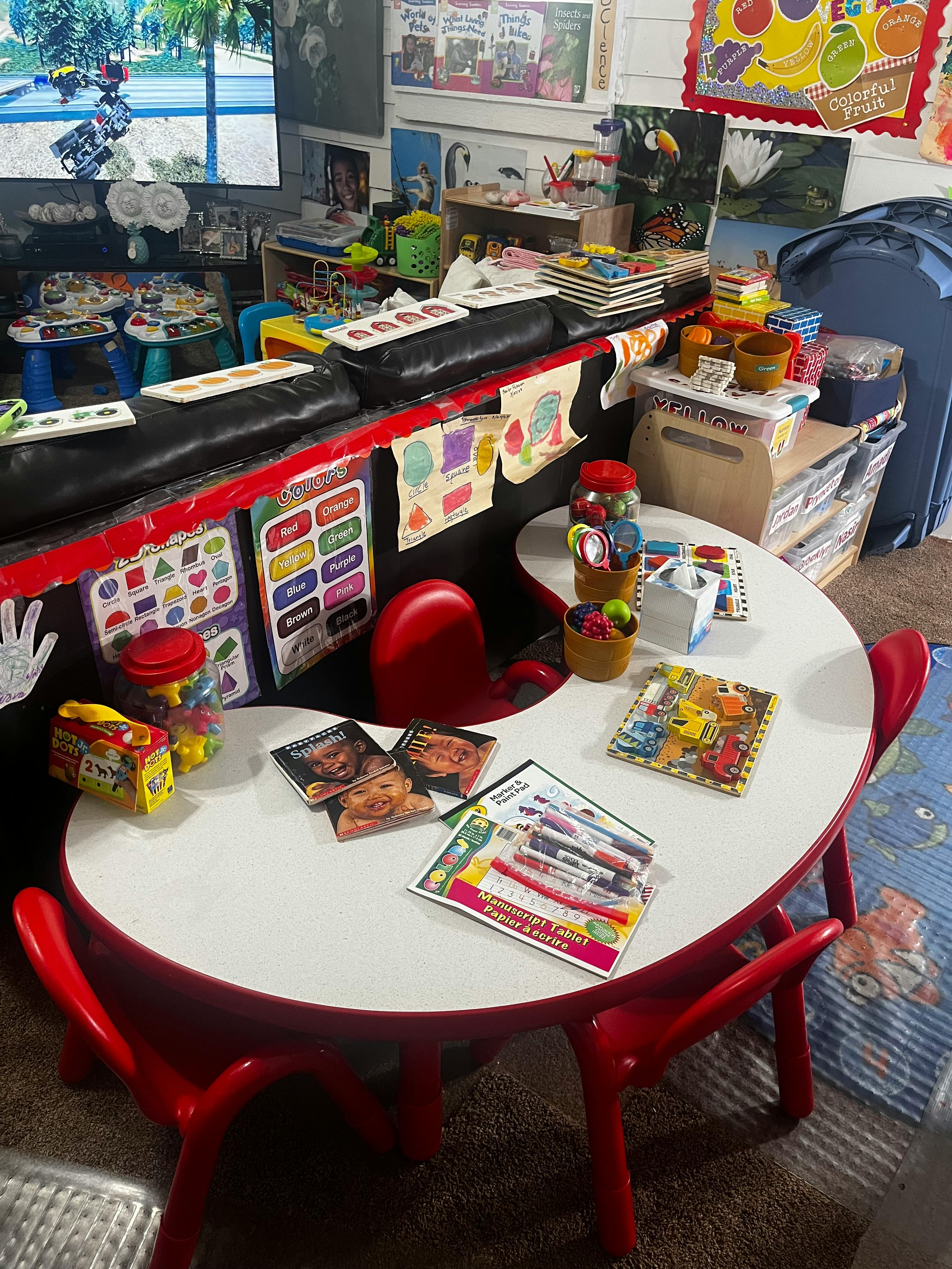 Classroom with a white table and red chairs, learning materials on walls
