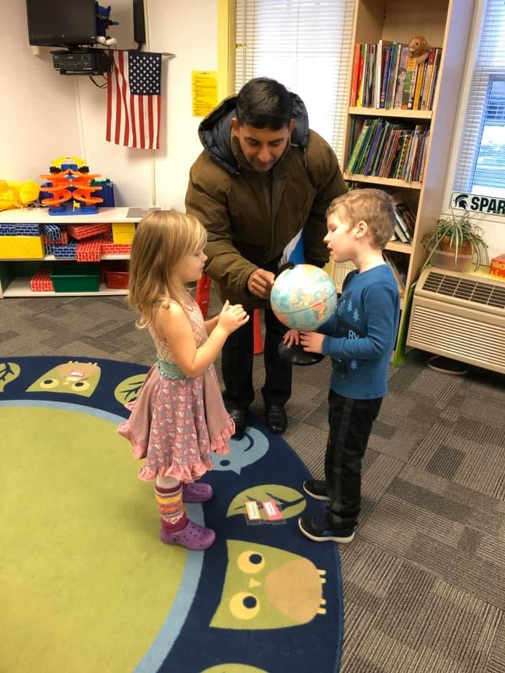 Adult and two children looking at a globe in a classroom