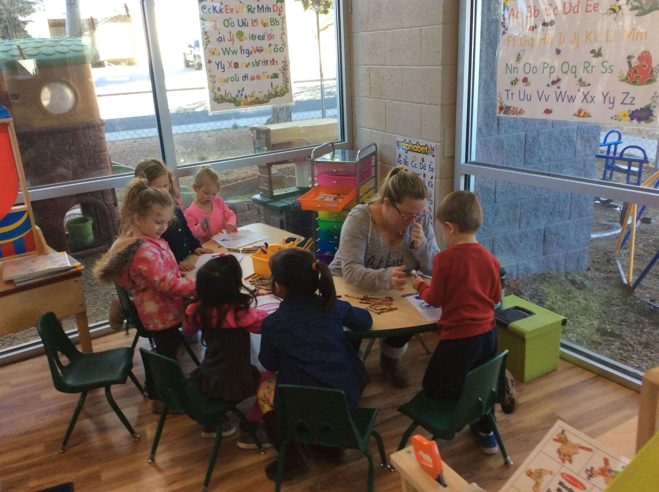 Adult and children sitting at a table in a classroom