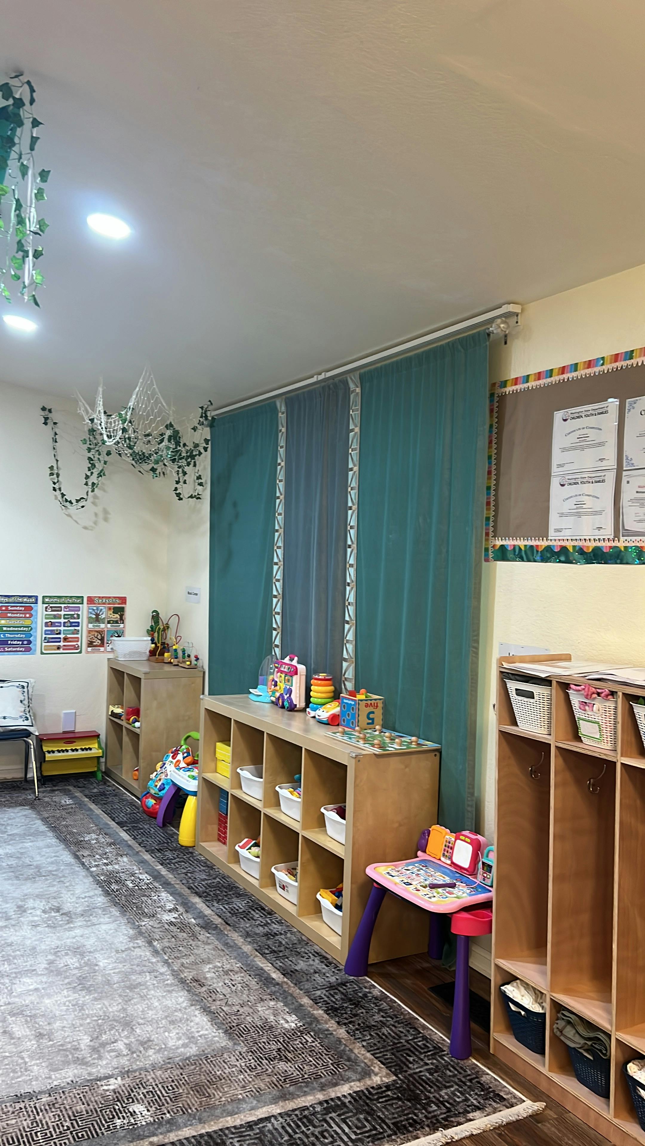 Classroom interior with toy storage shelves, rugs, and decorative curtains