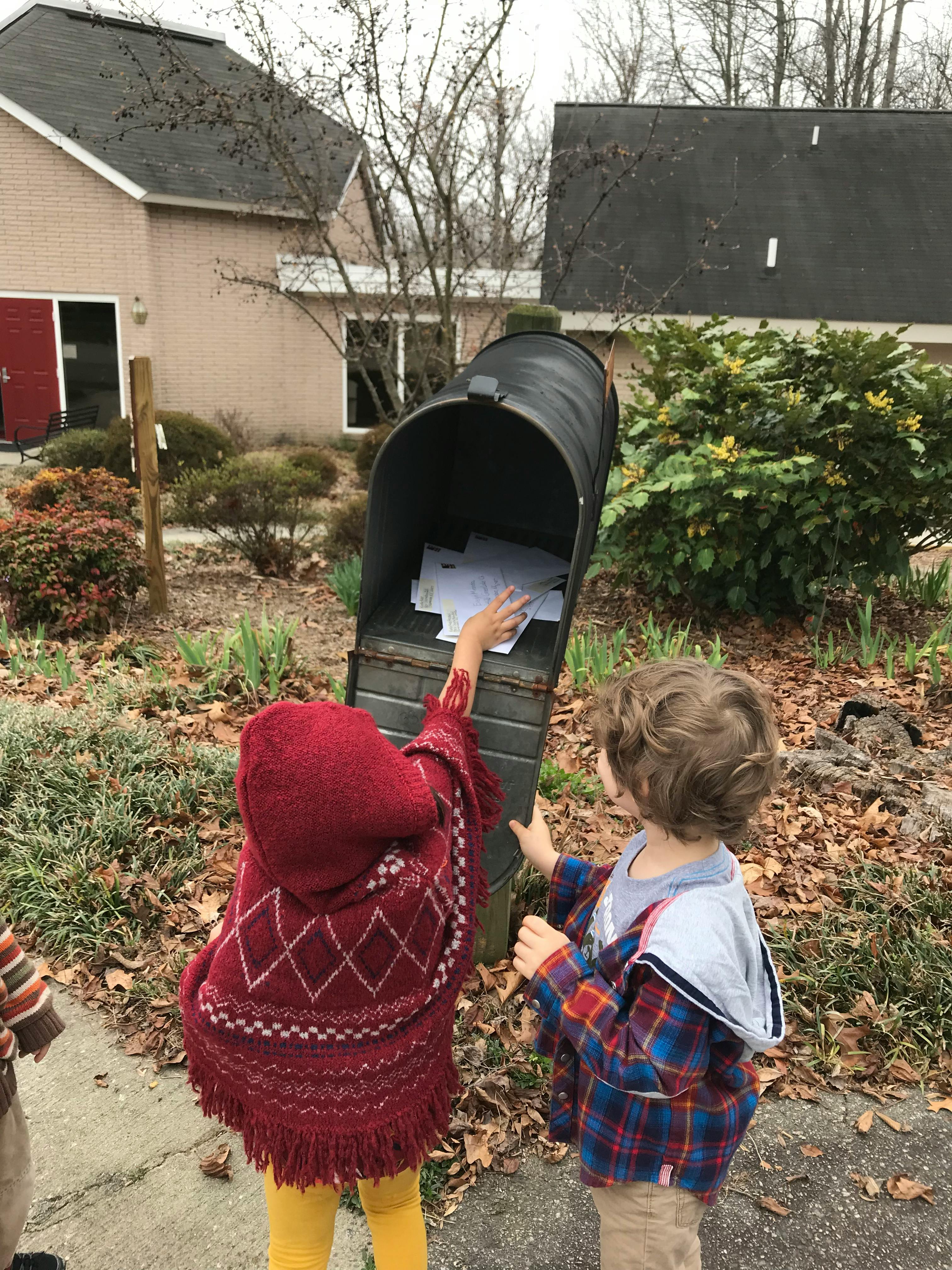 Two children reaching into an open mailbox