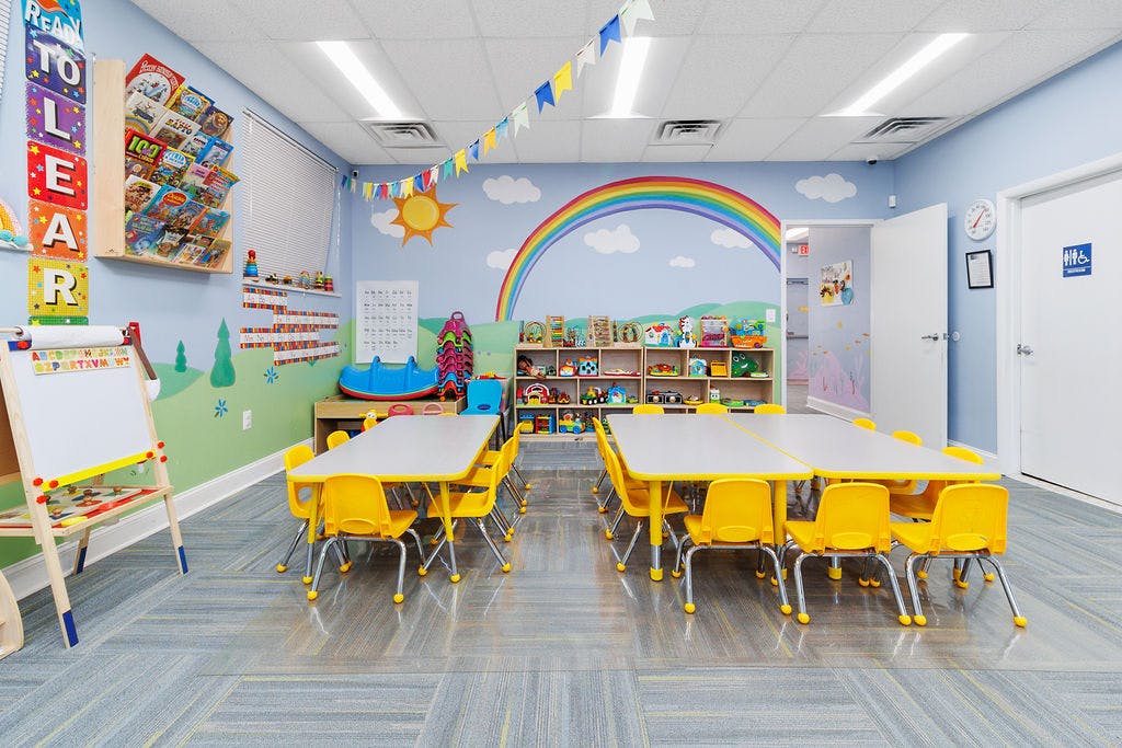 Classroom with small tables and chairs, colorful wall murals, and bookshelves