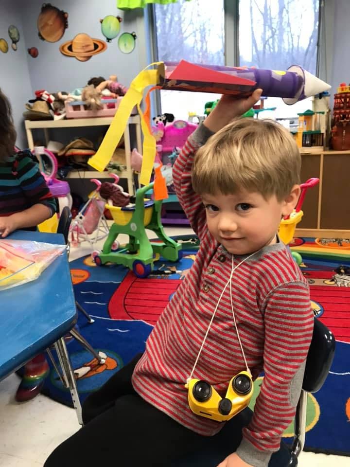 Child holding a homemade rocket above their head