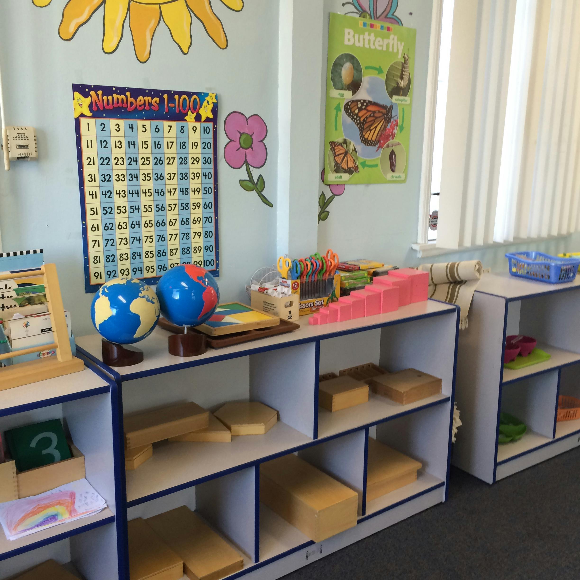 Classroom with globes, number chart, and shelves of learning materials