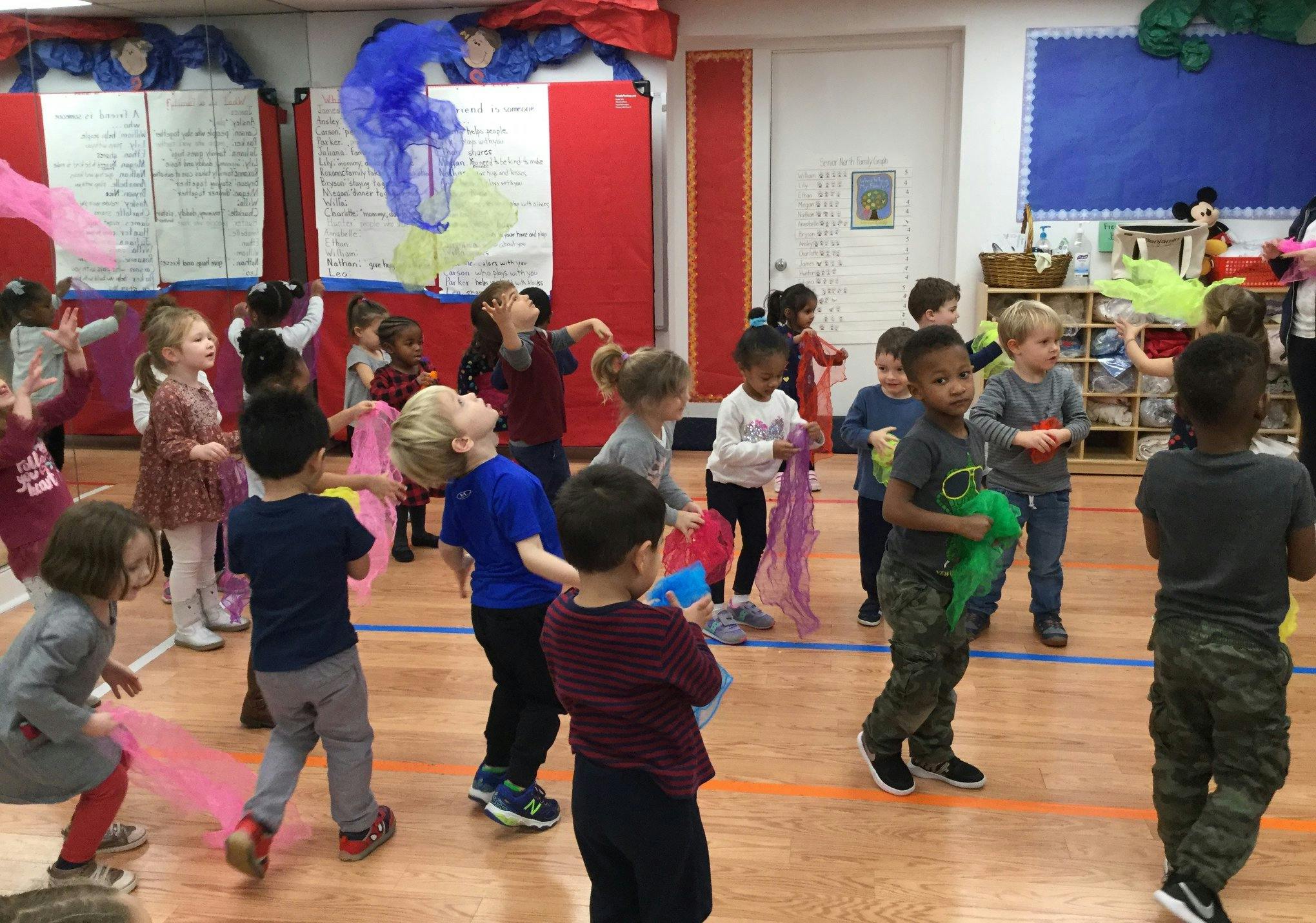 Children playing with colorful scarves in a classroom