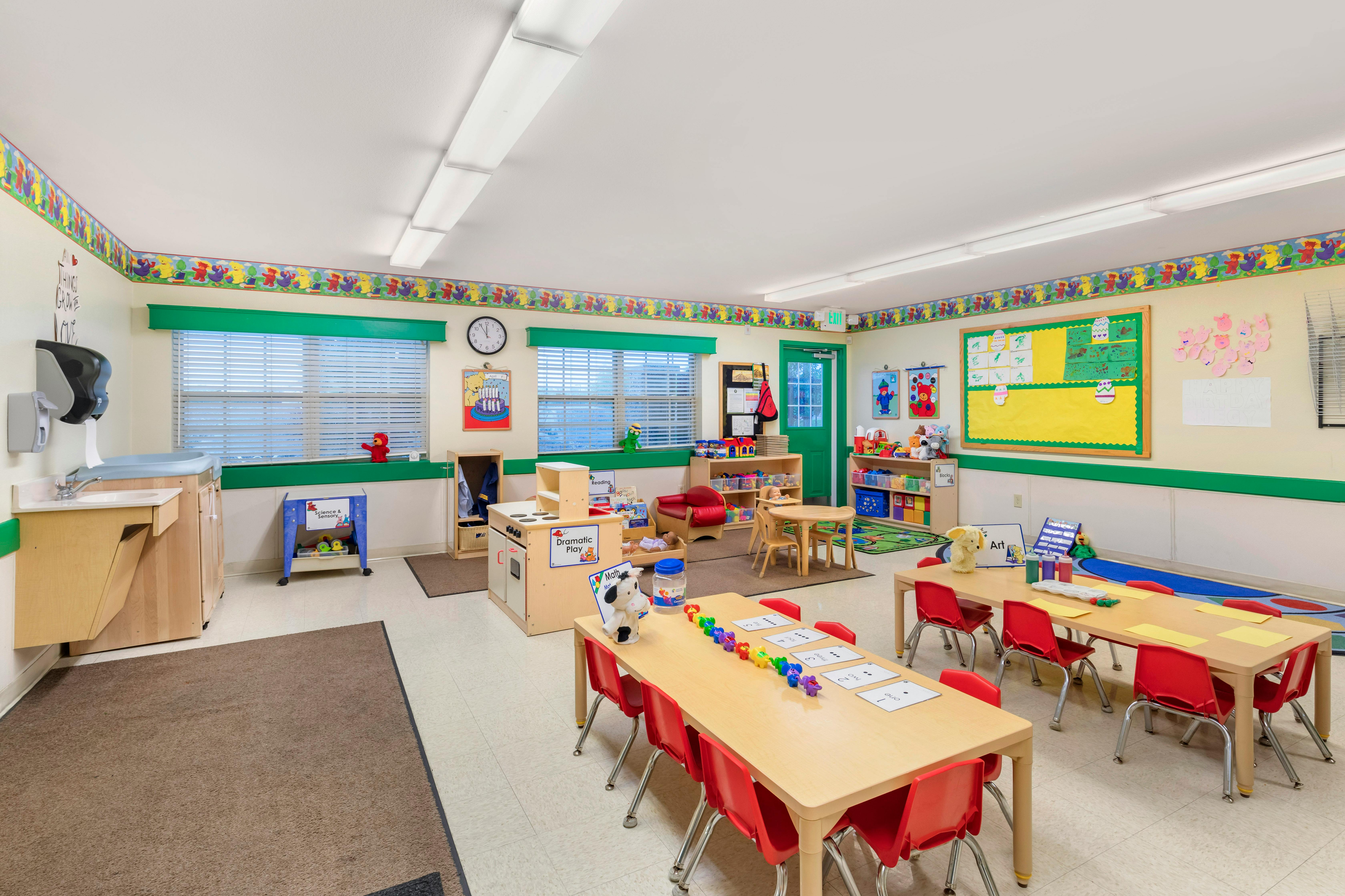 Classroom with child-sized tables and chairs, play kitchen, and colorful decorations