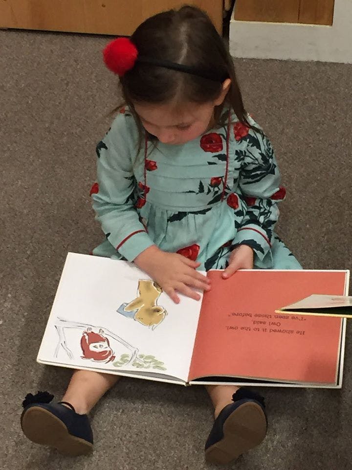 Child sitting on floor reading a book
