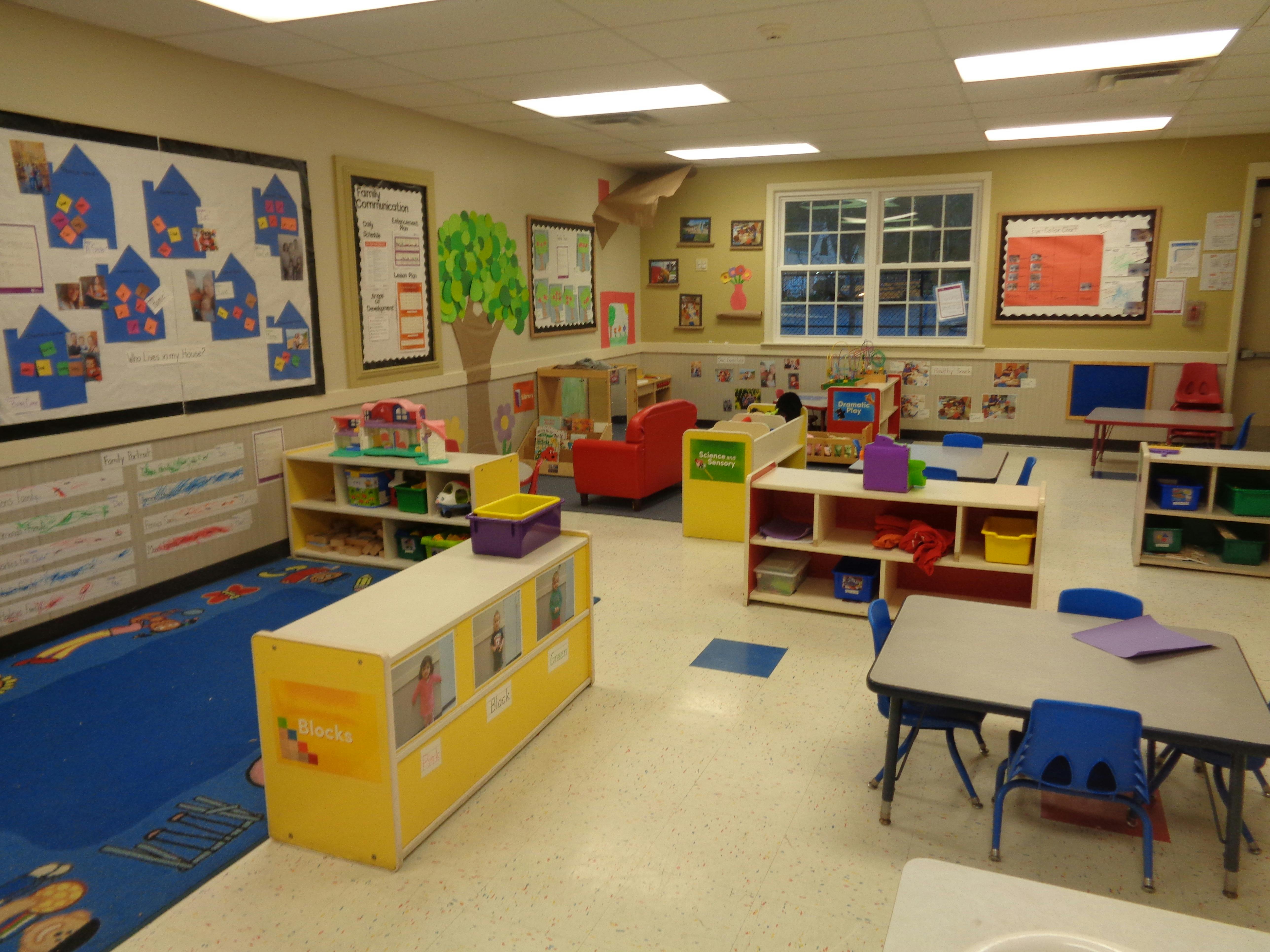 A colorful empty classroom with small tables, chairs, shelves, and learning stations
