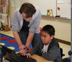 Adult and child looking at a laptop in a classroom