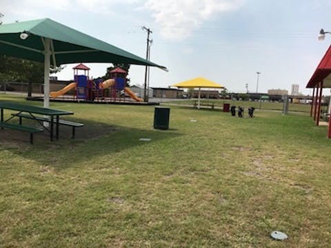 Playground with slides and climbing structures, picnic tables under shade