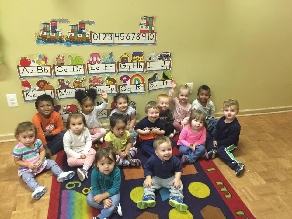 Group of children sitting on a rug in a classroom