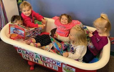 Children reading books in a bathtub with "Read a book in the tub" on it