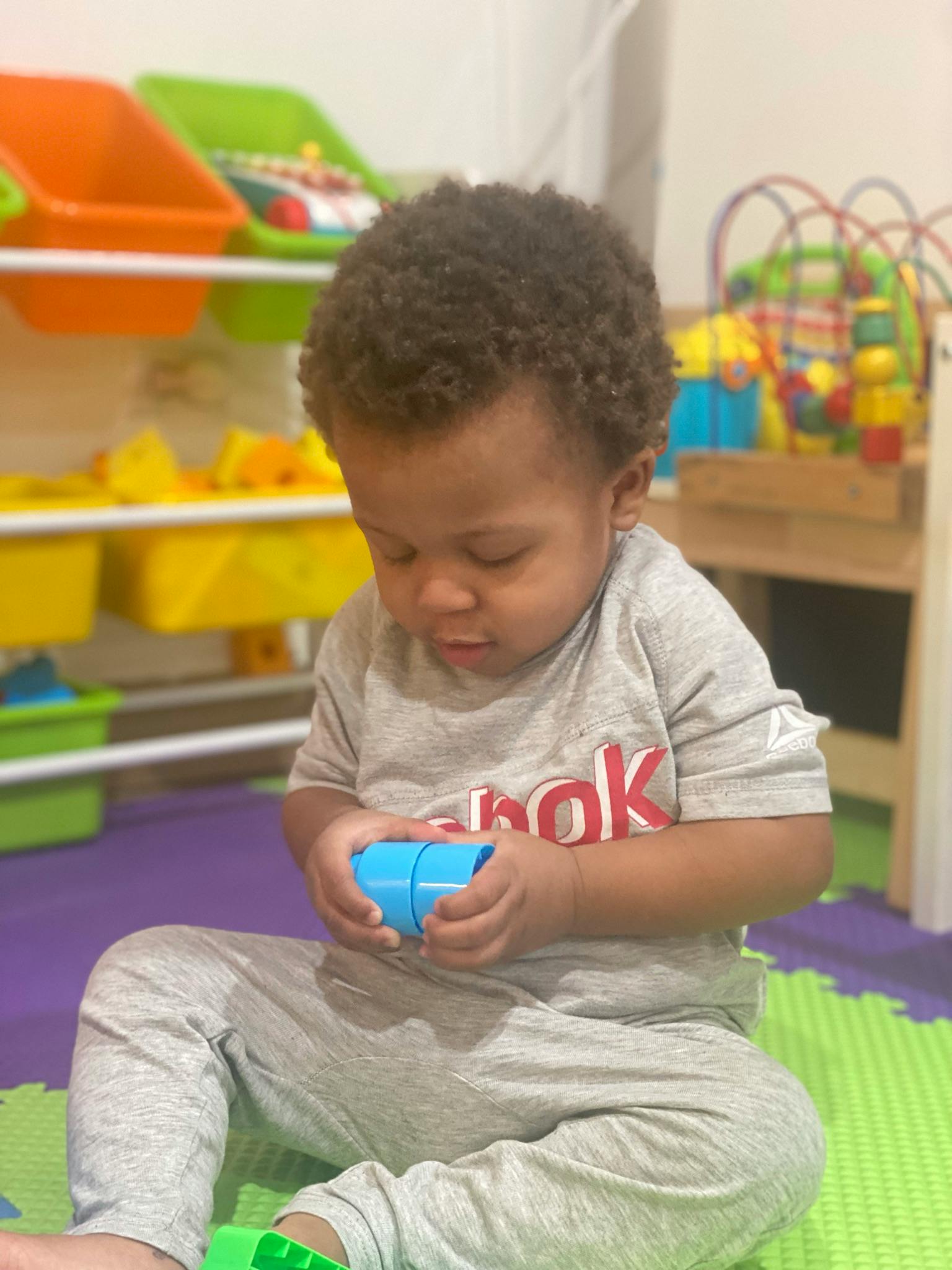 Child sitting on floor playing with blue toy blocks