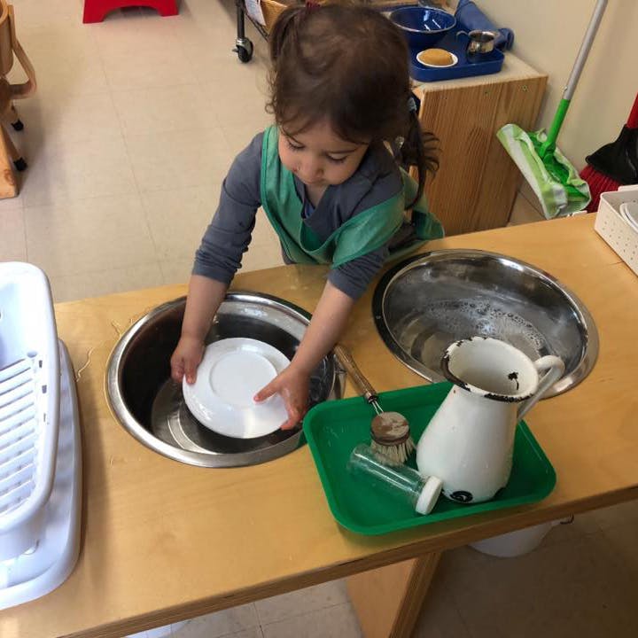 Child washing a plate in a sink