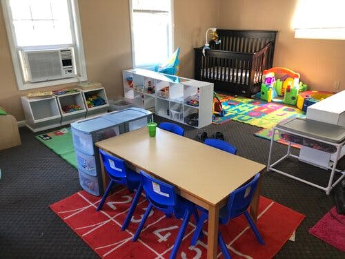 Childcare room with crib, playmats, and small table with chairs