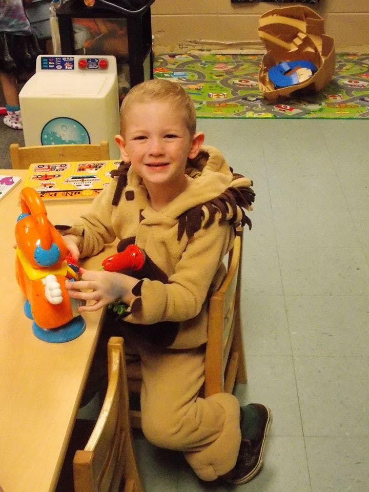 Child in costume sitting at a table with a toy