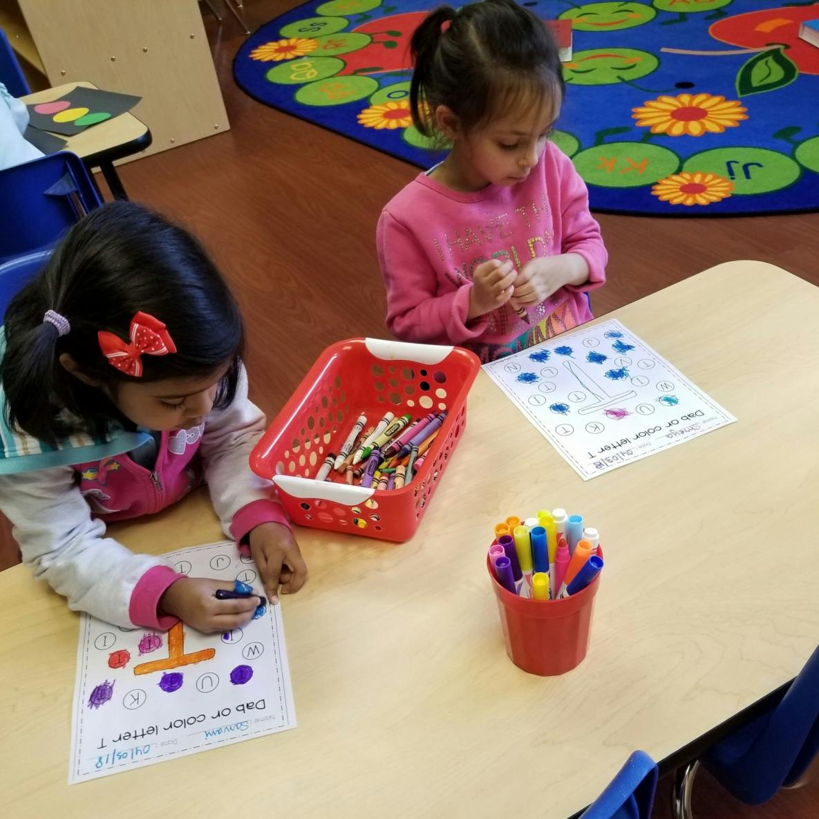Two children coloring at a table in a classroom