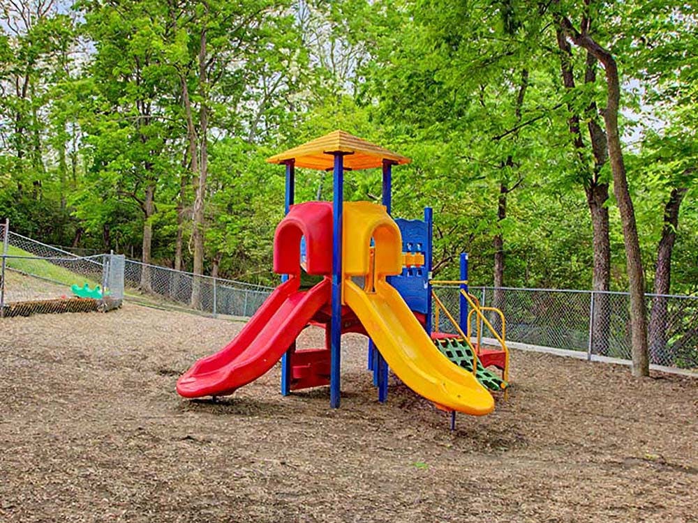 Colorful playground equipment with slides in a wooded area