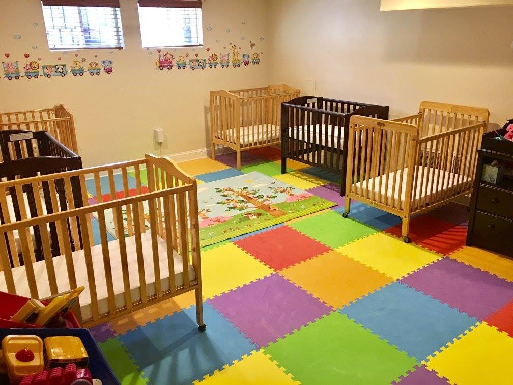 Nursery room with multiple cribs and colorful floor mats