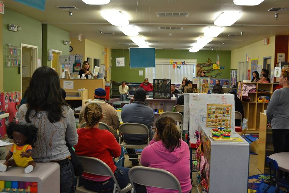 People seated in a room with a person speaking at a podium
