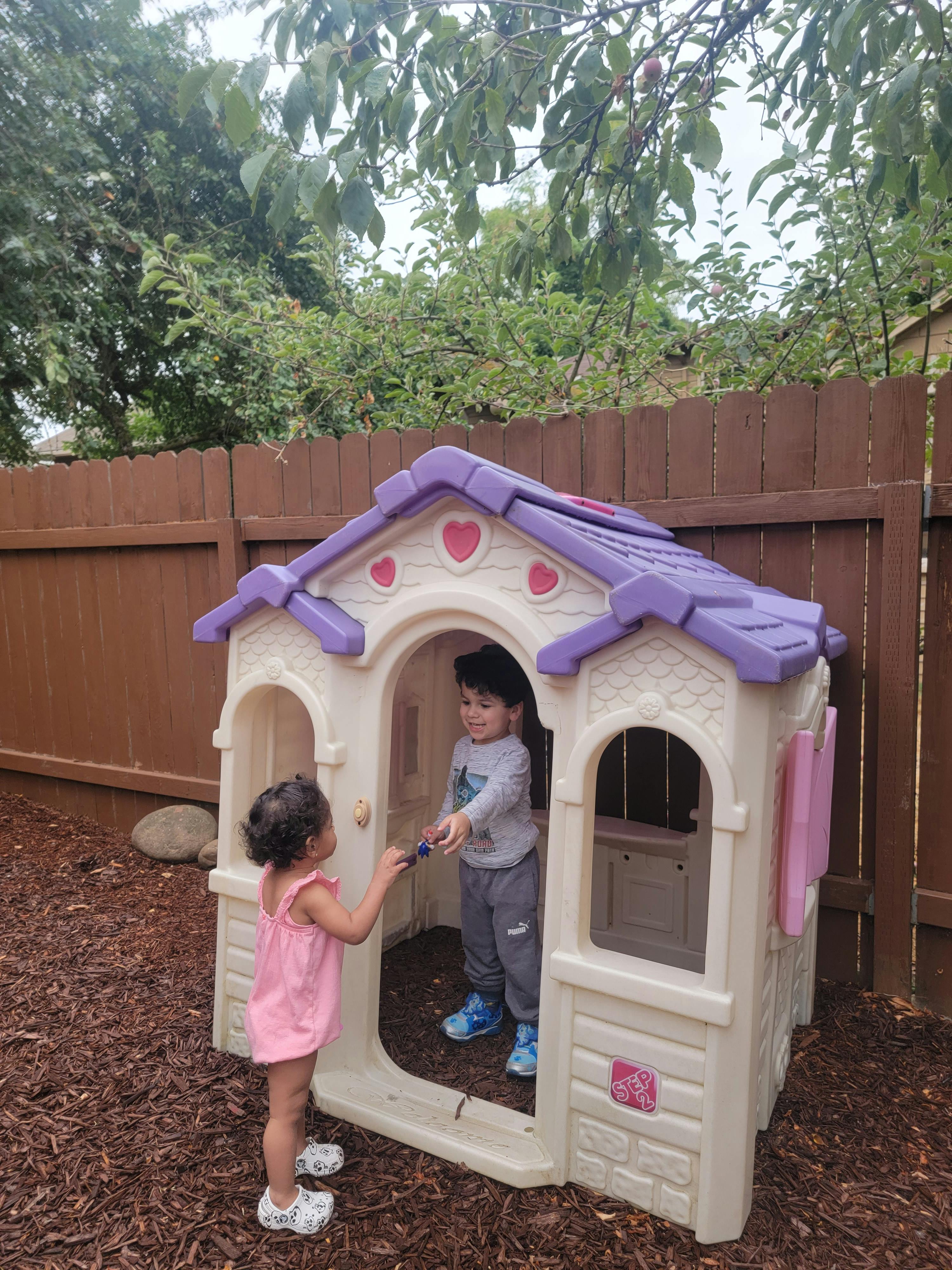 Two children playing with a toy house
