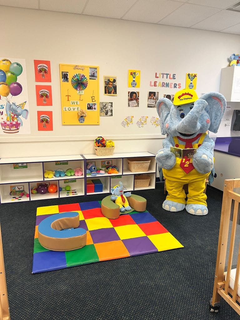 Elephant mascot in a classroom with a colorful playmat
