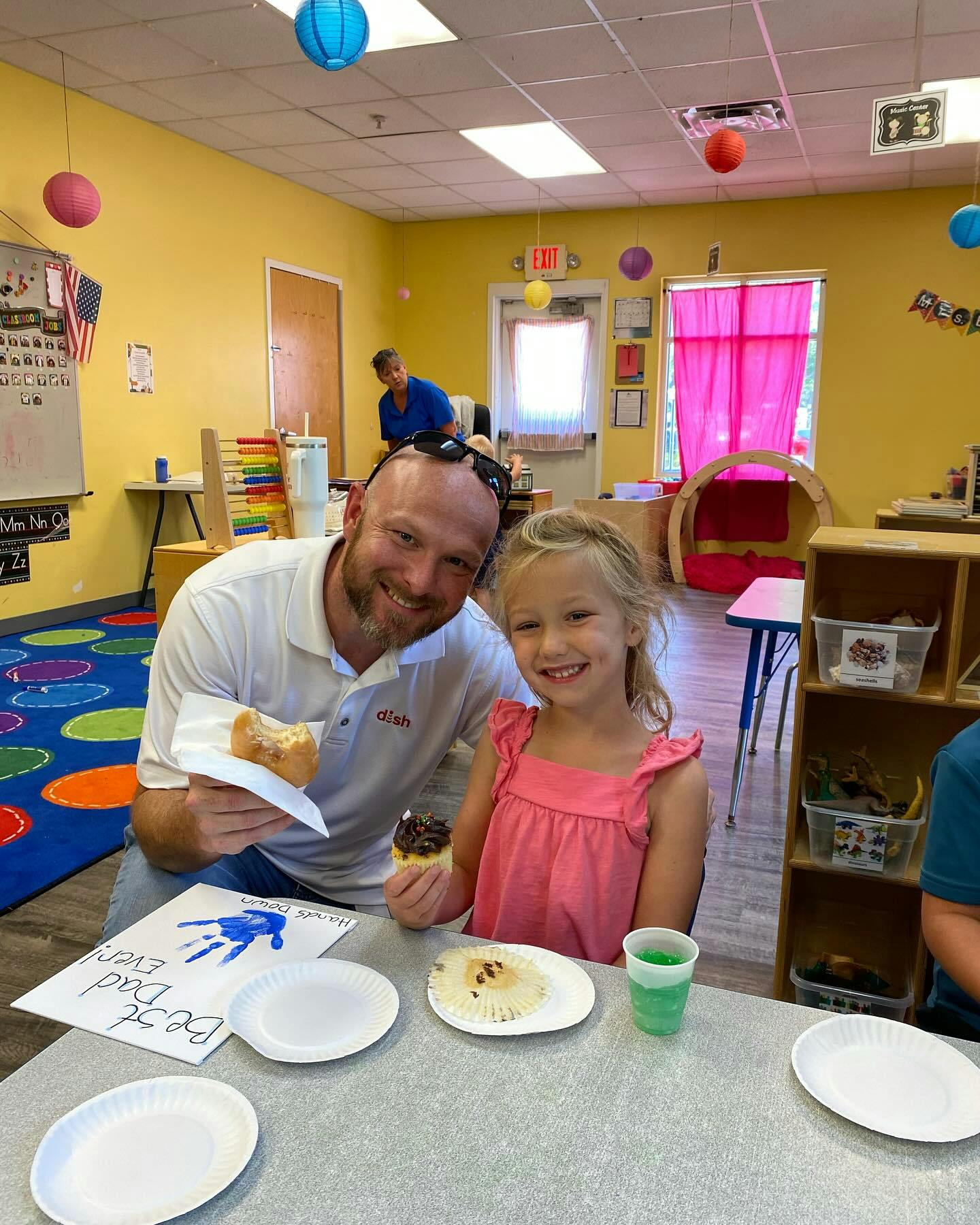 Adult and child sitting at a table with food and a craft