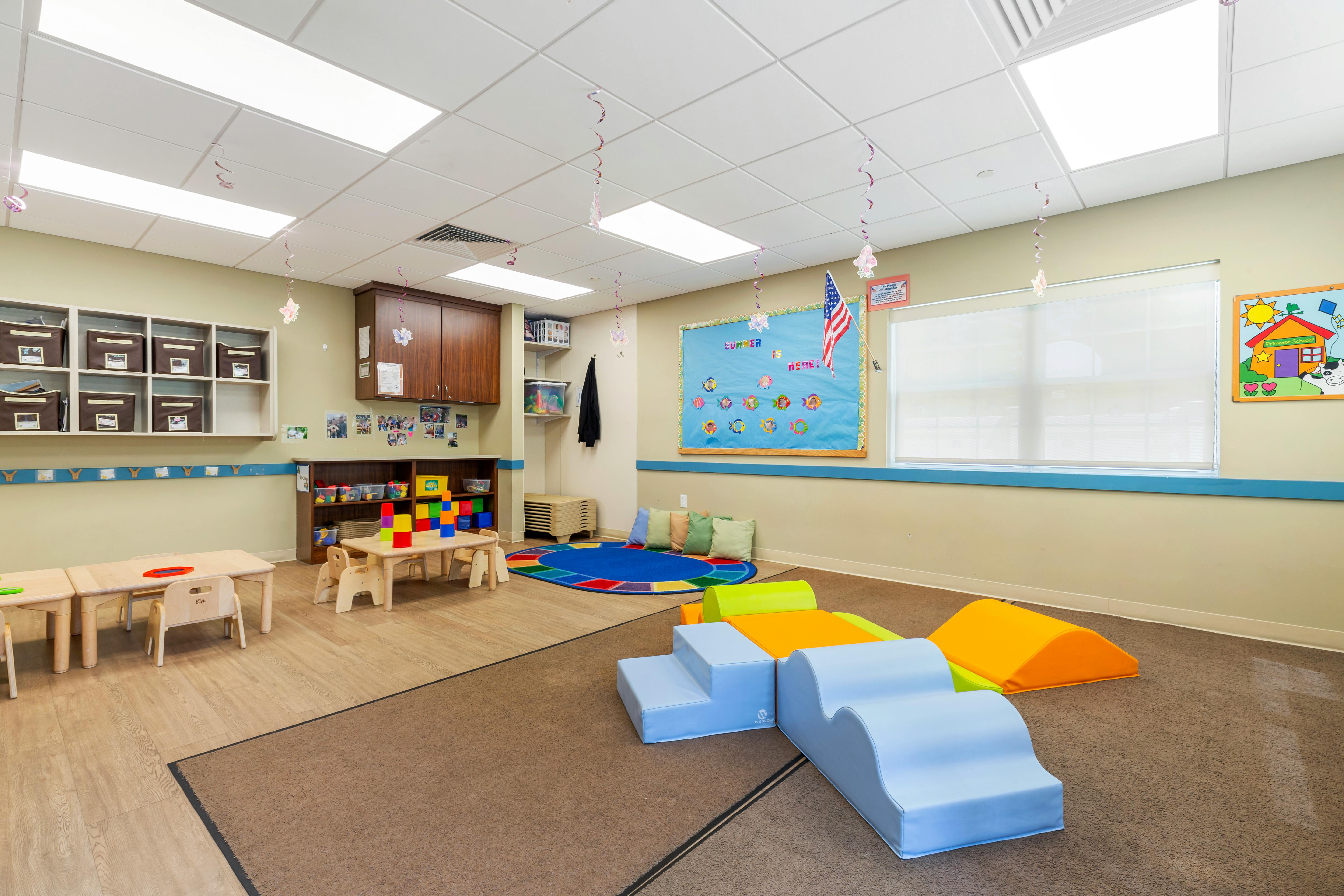 Classroom with small tables, chairs, and soft play equipment