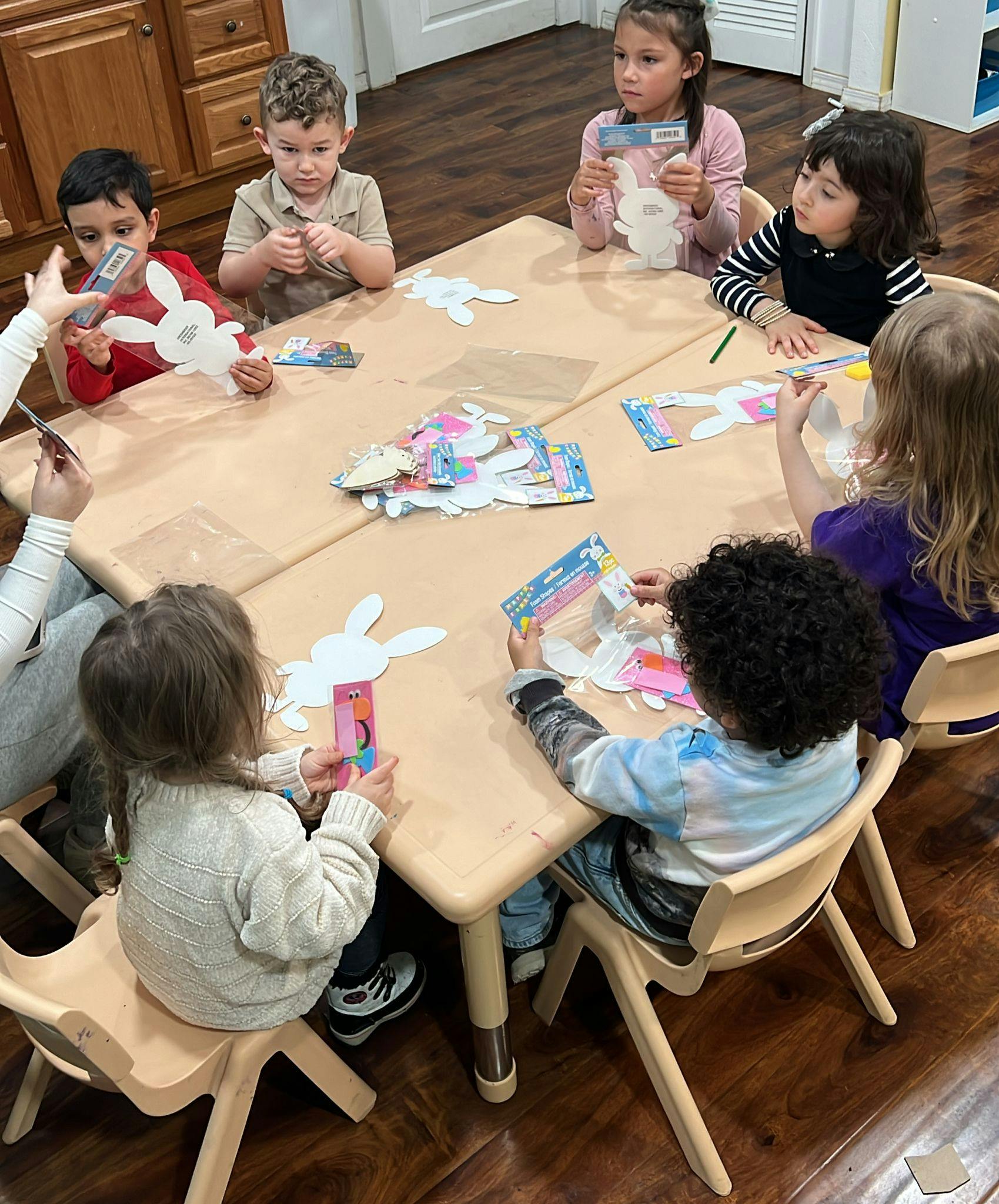Children at a table doing a craft with bunny cutouts