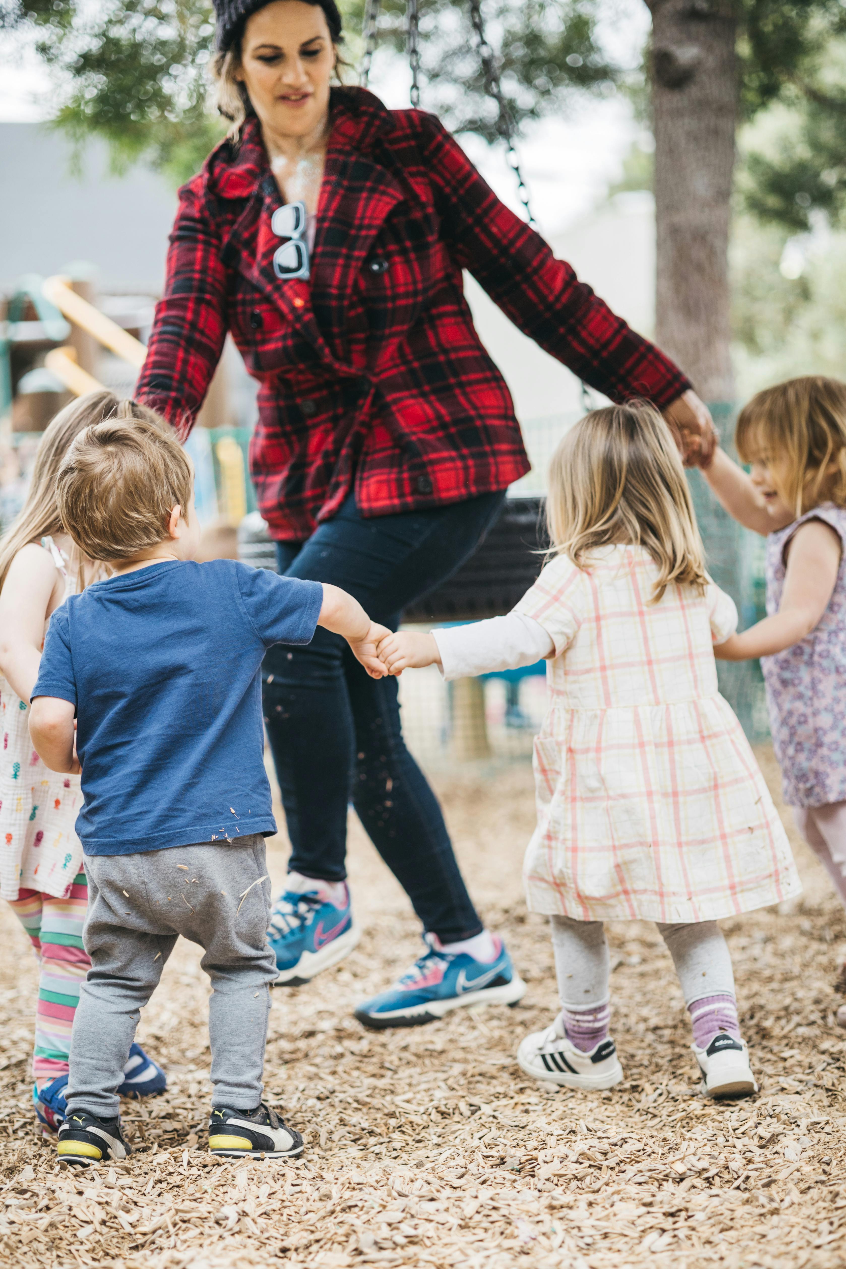 Person holding hands with three children in a circle
