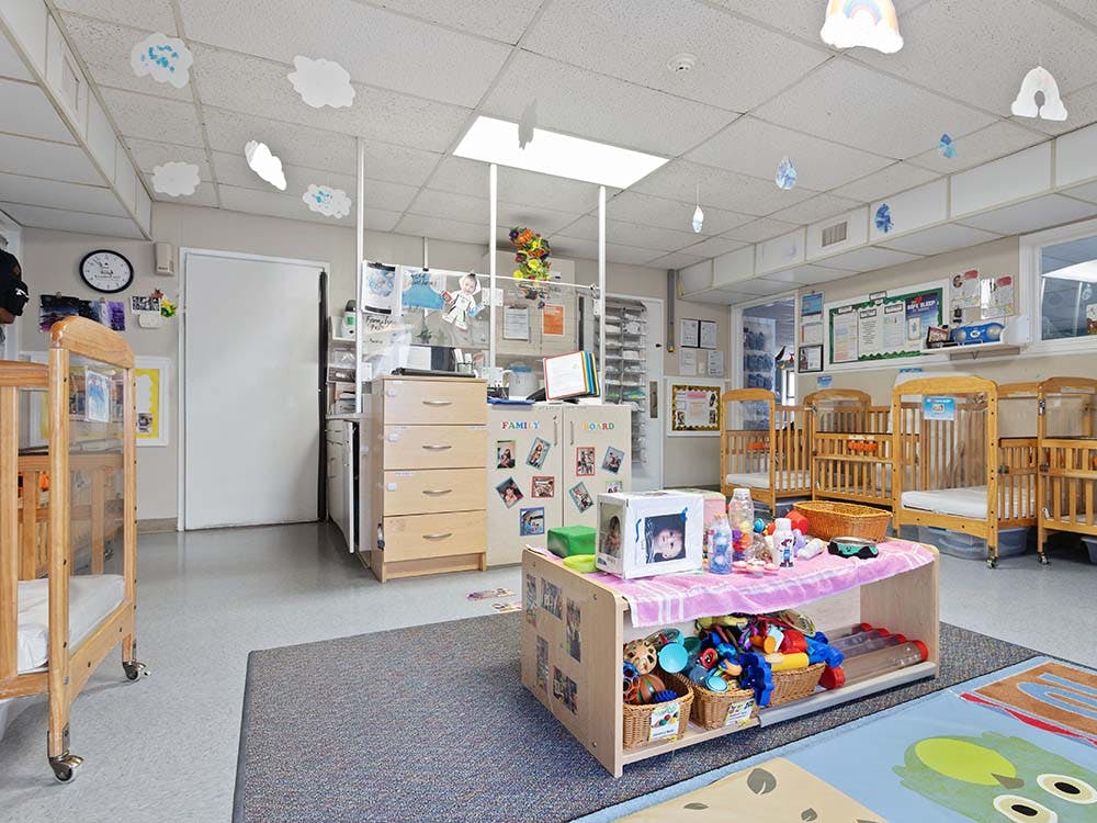 daycare room with multiple cribs, a changing station, and toys