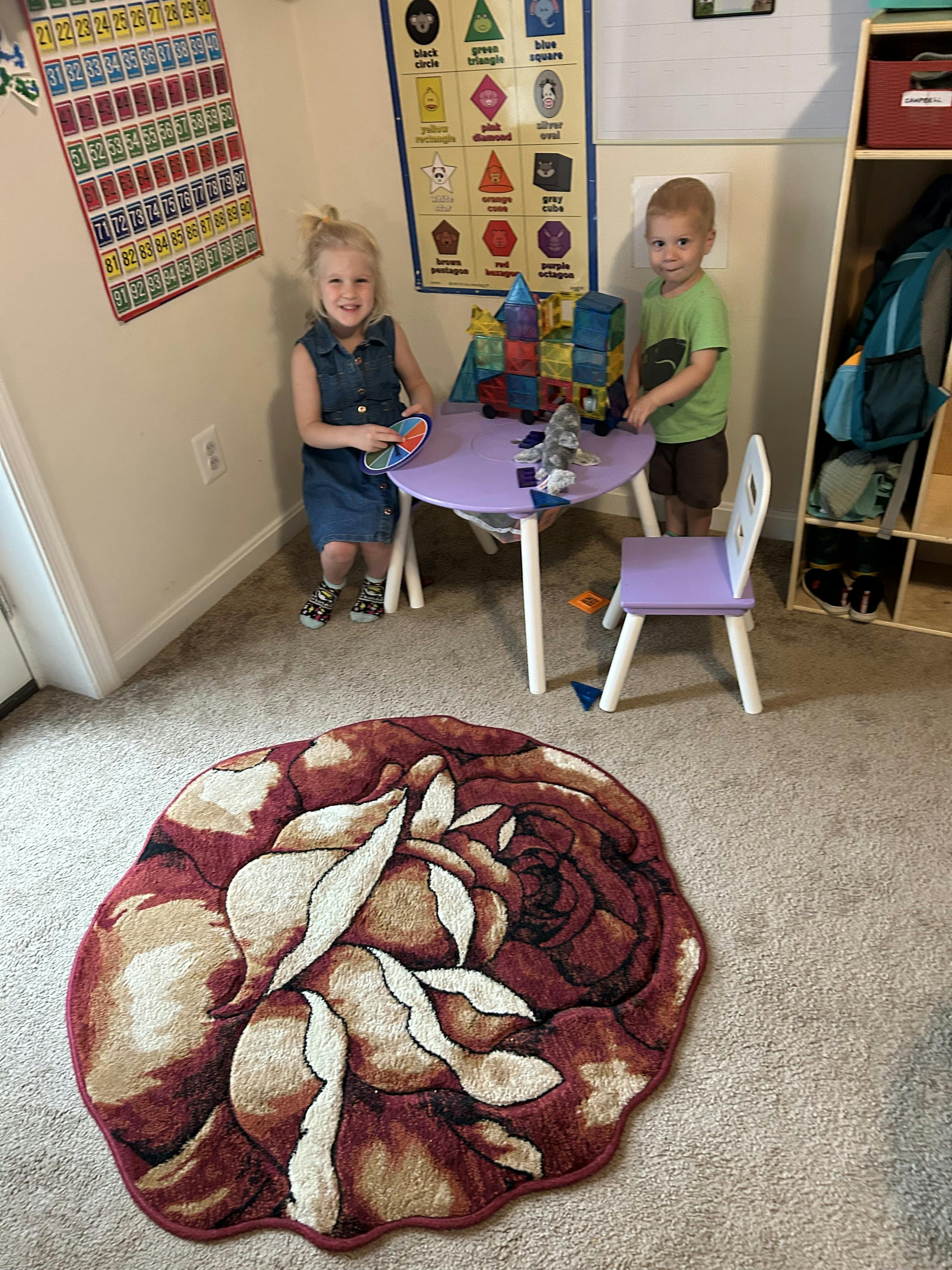 two children standing next to a table with magnetic building blocks