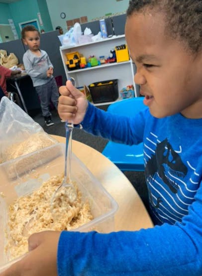 Child mixing food in a container with a spoon