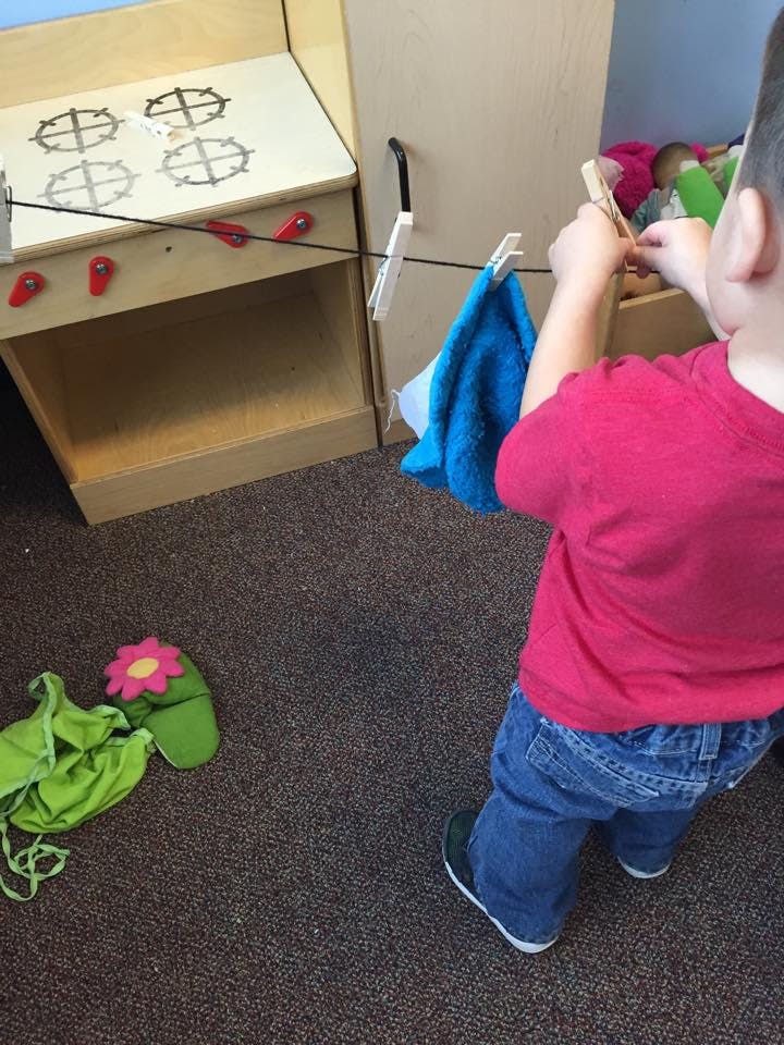 Child hanging laundry on a clothesline in a play kitchen