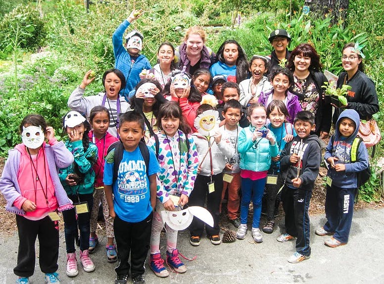 Group of adults and children, some wearing masks, standing outdoors