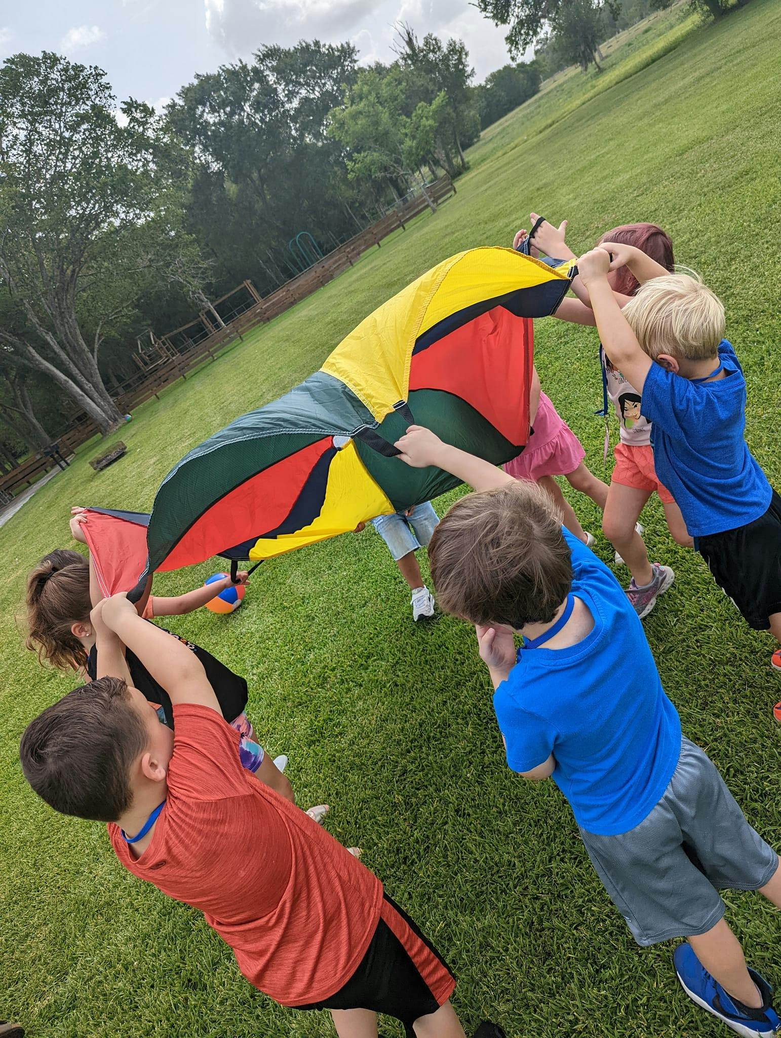 Children playing with a colorful parachute outdoors