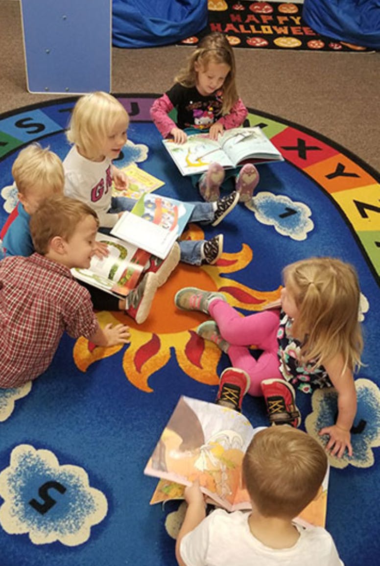 Children sitting on a colorful rug reading books