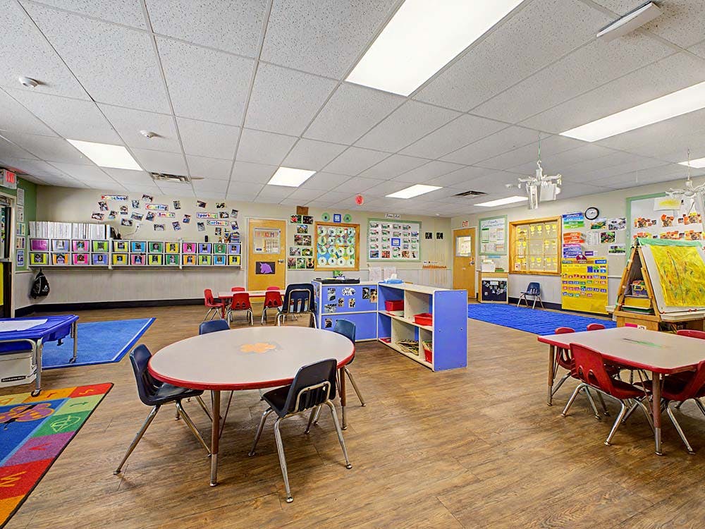 Empty classroom with small tables and chairs, artwork on walls