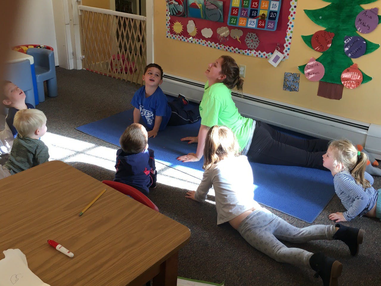 Adult and children doing yoga poses in a classroom