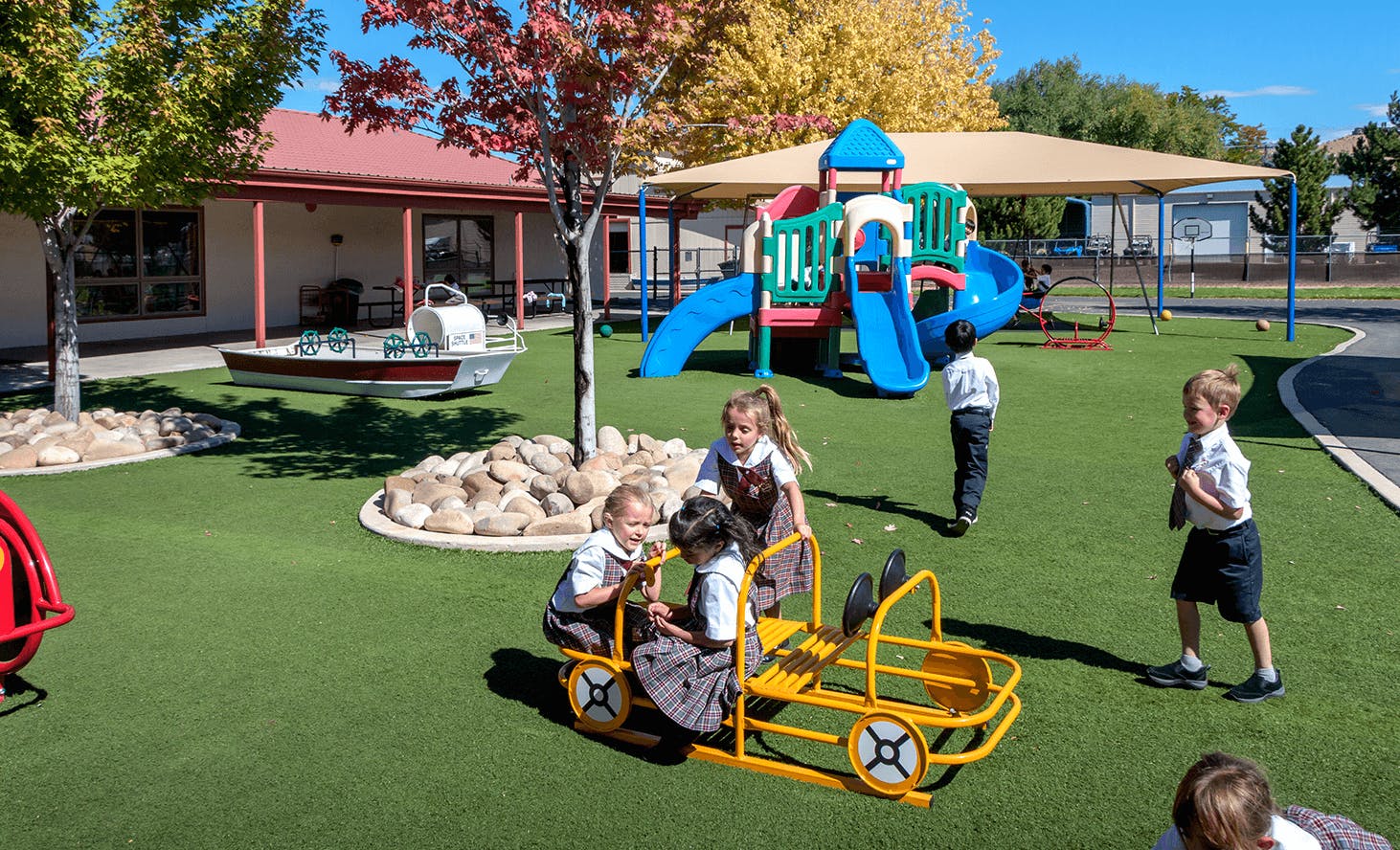 Children playing on a playground with a yellow ride-on toy and slide structure