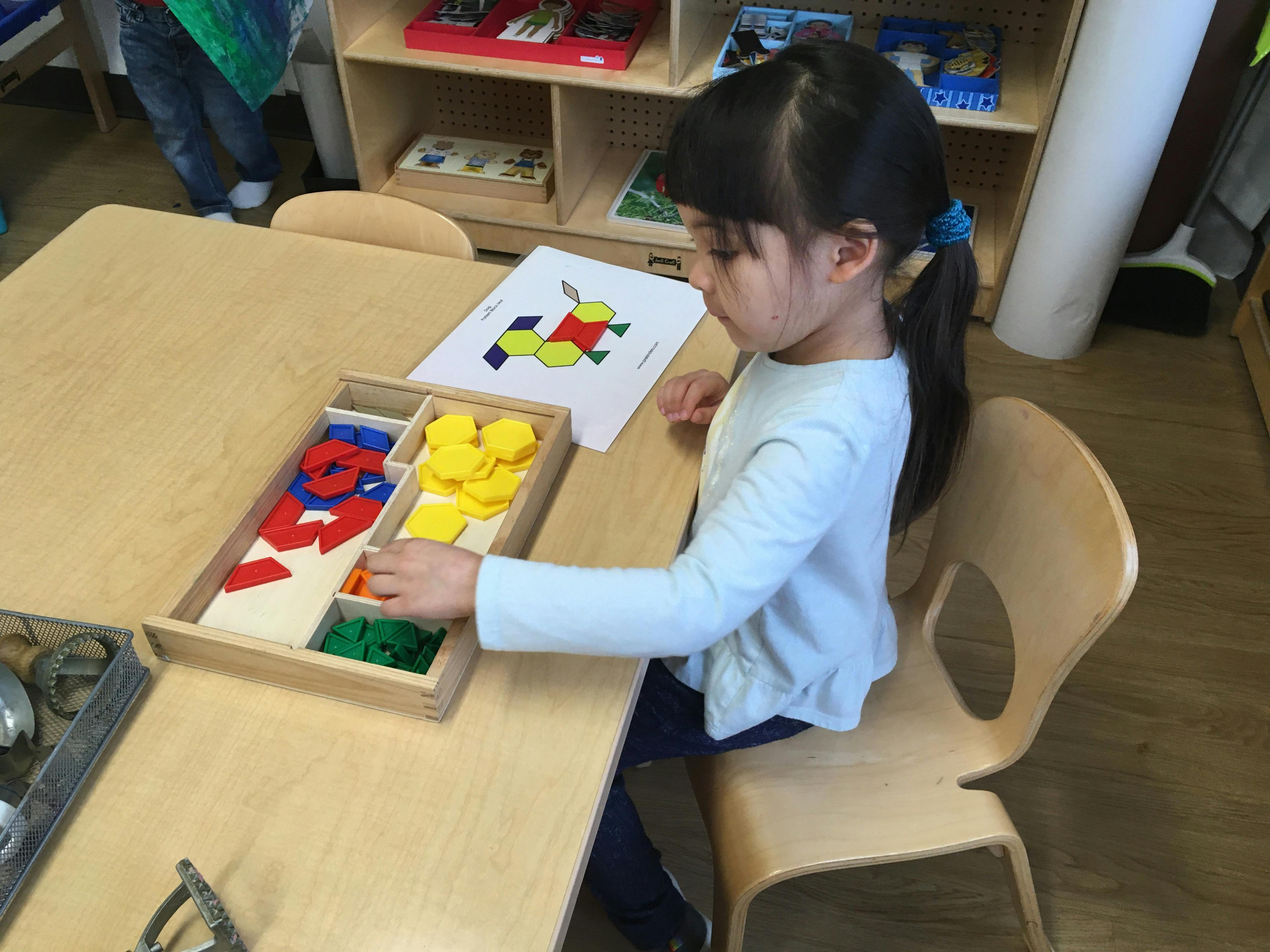 Child at a table playing with colorful geometric shapes